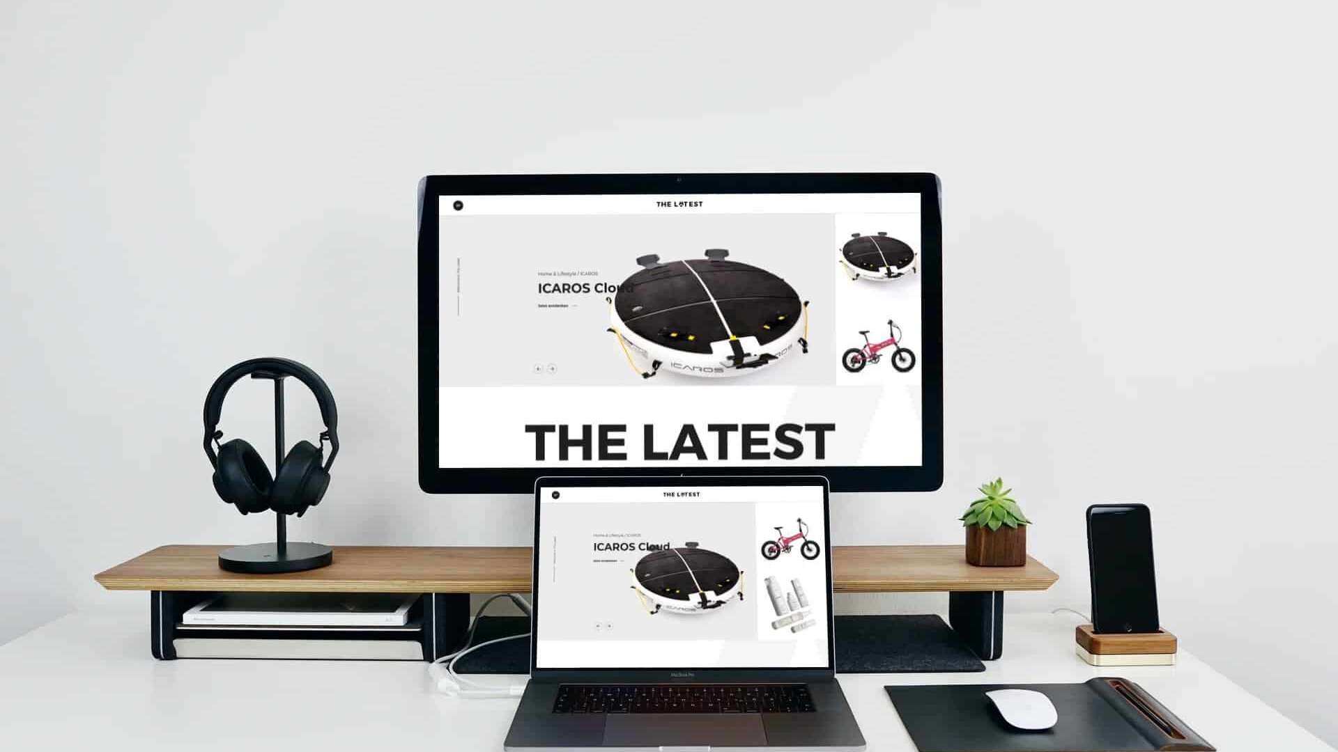 Mockup eines Schreibtischs auf dem ein Monitor, ein , ein Laptop, ein Smartphone, Over-Ear-Kopfhörer und eine Maus stehen. Gezeigt wird auf den Monitoren The Latest.