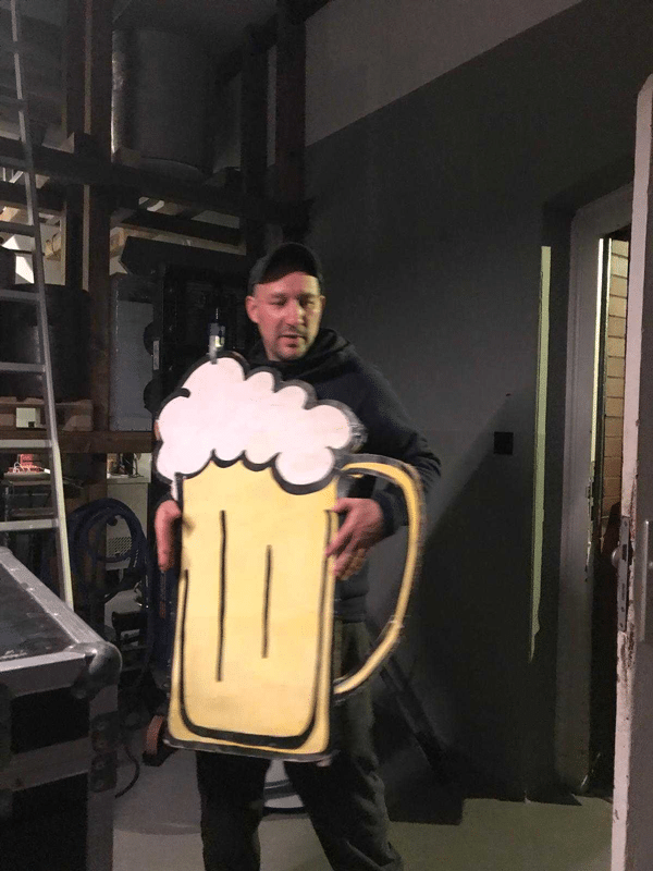 Backstage, Angestellter von Heiden Peters in schwarzer Kleidung tr&auml;gt ein Schild in Bierform.
