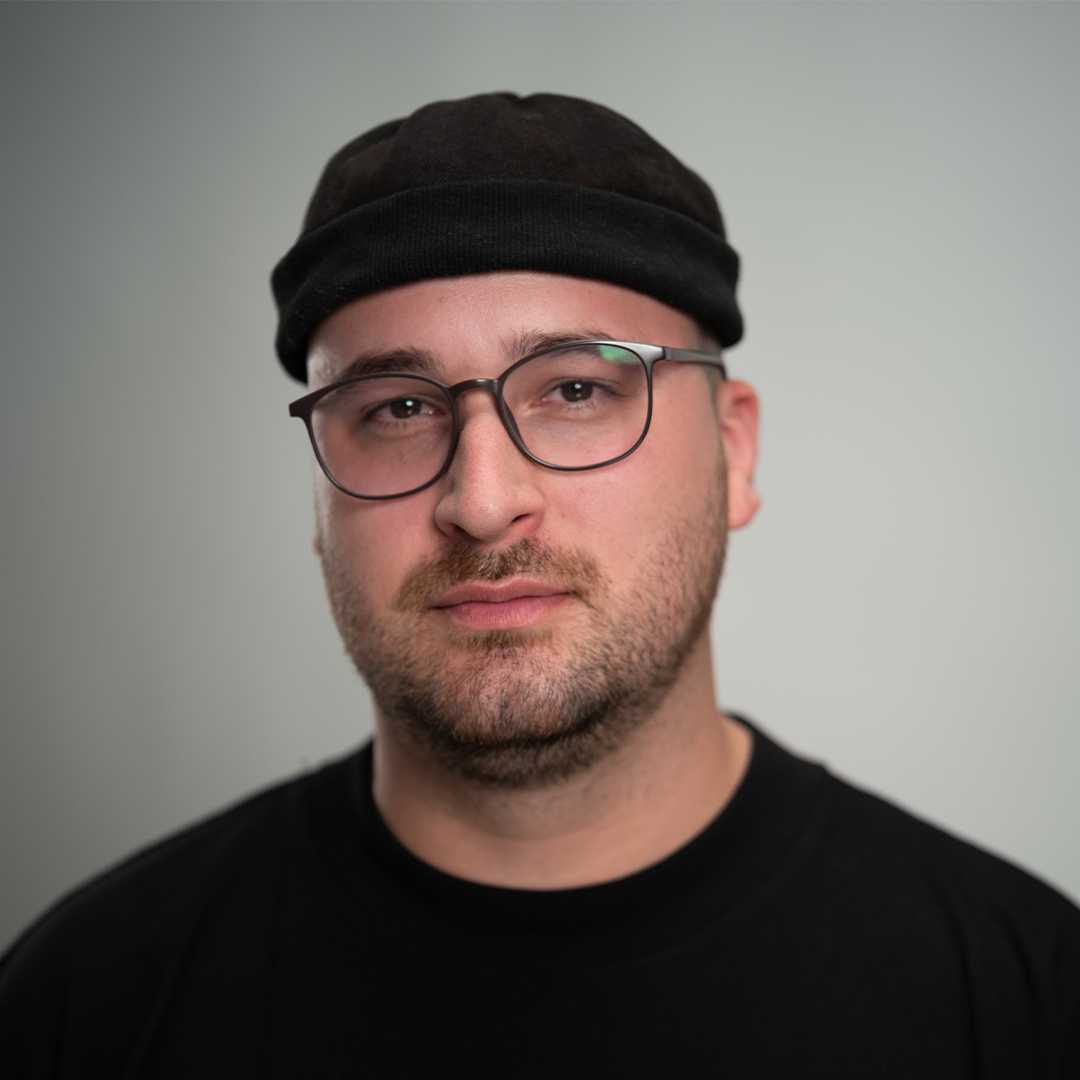 Portrait von Florian Rakette, Mitarbeiter von Knorke Media. Er trägt eine schwarze Mütze, schwarze Brille und schwarzes Shirt.